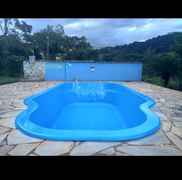 Piscina de fibra azul instalada com piso de pedra